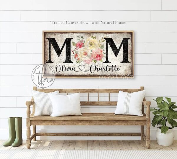 Toe Fish Art's unique, artisan-made Vintage Flower Bouquet "MOM" sign personalized with hand-lettered cursive family names to fit your style. This custom wall art is available as a wood-framed canvas with choice of framing colors, or outdoor waterproof metal, showcasing a worn rustic white background with bold black lettering and a beautiful painting of red, pink, and yellow roses. An ideal Mother's Day gift or any special occasion to celebrate Mom! Expertly made with American-sourced materials. This premium, handcrafted piece features a timeless aesthetic. Built to last with genuine craftsmanship, it adds rustic charm and heritage quality to any space. Made in the USA with durable, authentic materials for a beautiful and meaningful display. Rustic Cottagecore Country and Modern Farmhouse wall decor handcrafted in durable high-quality framed canvas or outdoor weatherproof solid aluminum metal, handmade in the USA from start to finish! Beautiful, stylish and timeless floral wall decor painting. Handcrafted in the USA by ToeFishArt, and built to last a lifetime by the Toe Fish Art family artisans. This beautiful original artwork adds unique eye-catching decor indoors or outdoors. Add instant outdoor curb appeal to your home! Perfect for your porch, entryway, patio, lanai, deck, garden, courtyard, gazebo, pergola, living room, fireplace hearth or mantel, wall hanging or shelf sitter, dining room or bedroom. This painting is a beautiful reminder of the gift of Mom's love to celebrate her for Mother's Day and all-year long. Original, custom, personalized wall decor signs. Canvas, Wood or Metal. Rustic modern farmhouse, cottagecore, vintage, retro, industrial, Americana, primitive, country, coastal, minimalist. Toe Fish Art is a USA small family woman owned business making beautiful decor since 1997.